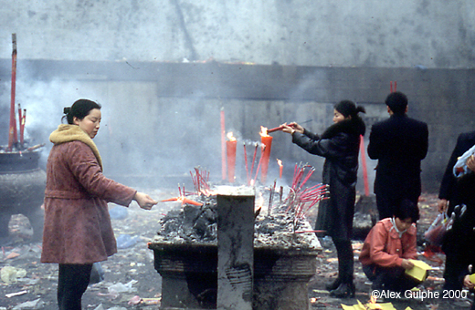 Photographie Couleur - Horizontale - Femmes faisant offrande de bougies et de bâtons d’encens dans un temple bouddhiste