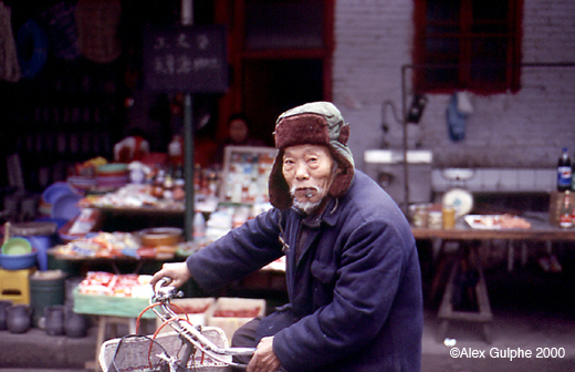 Photographie Couleur - Horizontale - Vieil homme à bicyclette devant un bazar