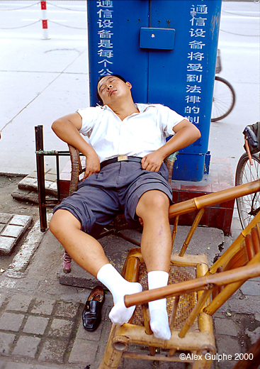 Photographie Couleur - Verticale - Homme endormi dans la rue sur deux chaises en bambou