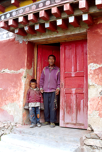 Photographie Couleur - Verticale - Jeune enfant et homme avec un chapelet à la main à l’entrée d’un monastère bouddhiste