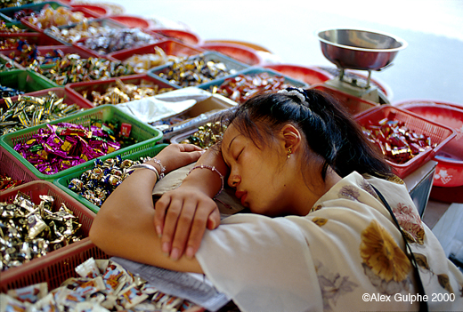 Photographie Couleur - Horizontale - Jeune marchande de bonbons endormie sur son étal