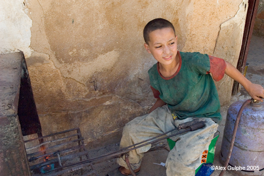 Photographie Couleur - Horizontale - Dinanderie, jeune ouvrier chargé du chauffage des pièces de métal