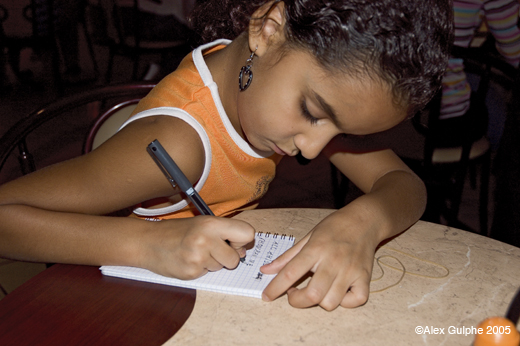 Photographie Couleur - Horizontale - Petite fille dans un restaurant rédigeant un petit lexique arabo-français