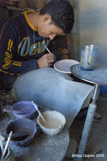 Photographie Couleur - Verticale - Artisan potier dans son atelier préparant le décor d’une assiette pour l’émaillage
