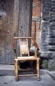 Photographie - Petite chaise en bambou devant une porte