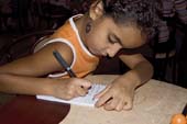 Photographie - Petite fille dans un restaurant rédigeant un petit lexique arabo-français
